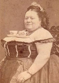 an old photo of a woman sitting in a chair with a cup on her lap