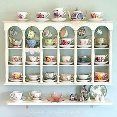 a white shelf filled with lots of cups and saucers