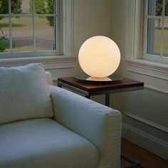 a white couch sitting next to a table with a lamp on it's side