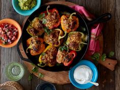 stuffed peppers in a skillet with salsa and guacamole on the side