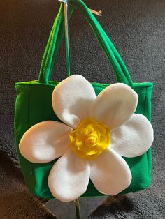 a green bag with a white flower on the front and yellow center in the middle