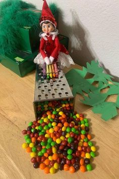 an elf is sitting on top of a box filled with candy