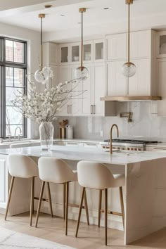 a kitchen with marble counter tops and white chairs in front of an island that has three stools on it