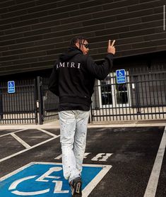 a man walking across a parking lot with his hand in the air