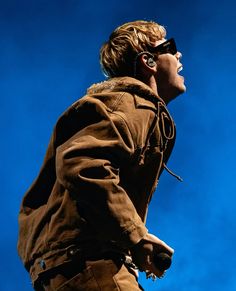 a man with sunglasses on his head is standing in front of a blue sky and looking up