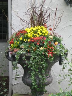 a large planter filled with lots of flowers sitting next to a white wall and door