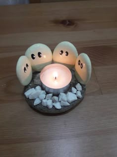 three eggs sitting on top of a stone with candles in it and rocks around them