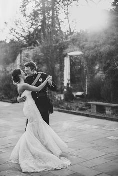 a bride and groom are hugging outside