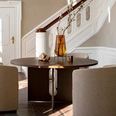 a table with two chairs and a vase on it in the middle of a room