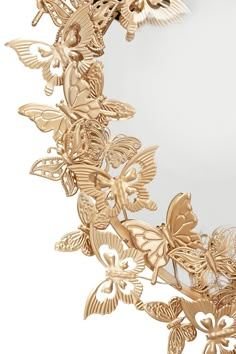 a mirror that has some gold butterflies on the frame and one is in the shape of a wreath