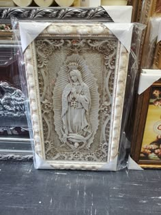 an image of the virgin mary on display in a store window with other items behind it