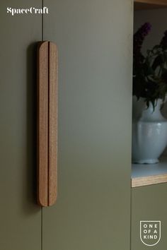 a close up of a wooden object on a wall near a vase with flowers in it