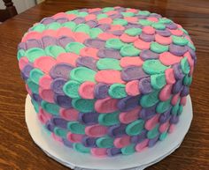 a cake that is sitting on top of a white plate with pink, green and purple icing