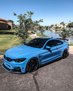 a blue bmw car parked in front of a body of water with trees around it