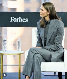 a woman sitting in a chair next to a table with a water bottle on it