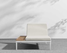 a white chair sitting on top of a wooden floor next to a wall with shadows