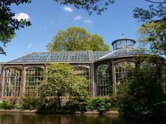 a large building with many windows and trees around it in the middle of a pond