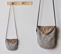 two purses hanging on the wall, one with a pocket and one without it