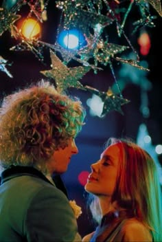 two women standing next to each other under a christmas tree