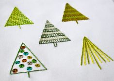 several different types of christmas trees on a white fabric piece with green and yellow trim