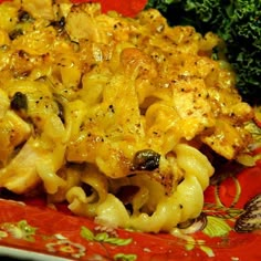 a red plate topped with macaroni and cheese covered in broccoli florets