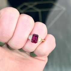 a woman's hand holding a ring with a pink tourmaline stone in it