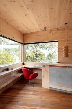 an empty room with a red chair and window overlooking the trees outside in front of it