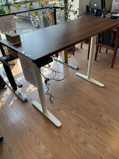 an office desk with several electronic devices on it and people sitting at the table in the background