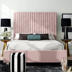 a pink bed with black and white pillows in a bedroom setting that is very stylish