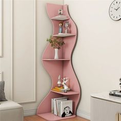 a pink curved shelf with books and decorations on it in the corner of a room