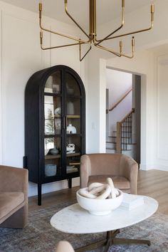 a living room filled with furniture and a chandelier hanging over the top of it