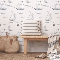 a wooden bench sitting in front of a wall with sailboats on it and a bag next to it