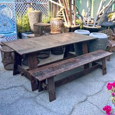 a wooden table and bench in front of potted plants