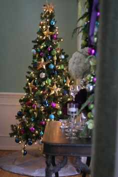 a decorated christmas tree sitting in the corner of a room next to a coffee table