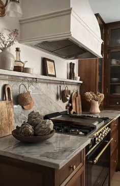 a kitchen with marble counter tops and wooden cabinetry, along with an oven hood