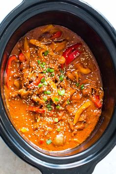 an overhead view of a crock pot filled with meat and vegetables, garnished with parsley