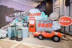 an orange toy car sitting on top of a table next to balloons and other items