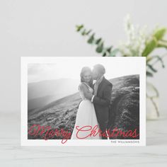 a christmas card with an image of a man and woman hugging each other on top of a hill