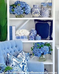 a blue and white living room with bookshelves filled with vases and flowers