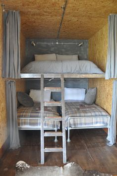 a bunk bed in a small room with curtains on the windows and a chair underneath it