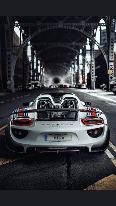 a white sports car parked on the side of a road next to an overpass