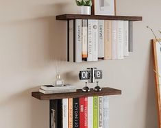 a shelf with books on top of it in front of a wall mounted clock and pictures