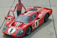 a man standing next to a red race car