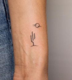 a small tattoo on the wrist of a woman with a cactus and sun in the background