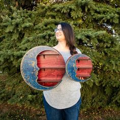 a woman holding two wooden boards in front of trees