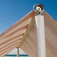 a close up view of the top of a beach umbrella with blue skies in the background