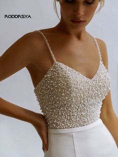 a woman wearing a white dress with beading on it