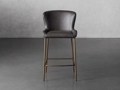 an upholstered bar stool in grey leather with gold legs and backrests