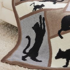 a crocheted afghan with cats and dogs on it is sitting on the floor