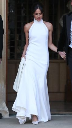 a woman in a white dress walking out of a building